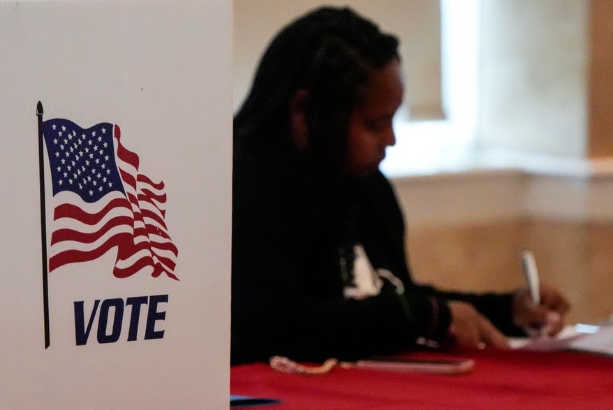 A Fulton County staff member works as people vote in a runoff election, Tuesday, June 16, 2026, in Atlanta. (AP Photo/Mike Stewart)