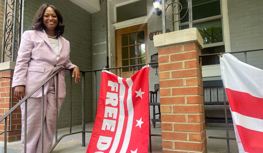 District of Columbia mayoral candidate Janeese Lewis George poses with a Free DC flag while canvassing in a Washington, neighborhood, Monday, June 15, 2026. (AP Photo/Matt Brown)