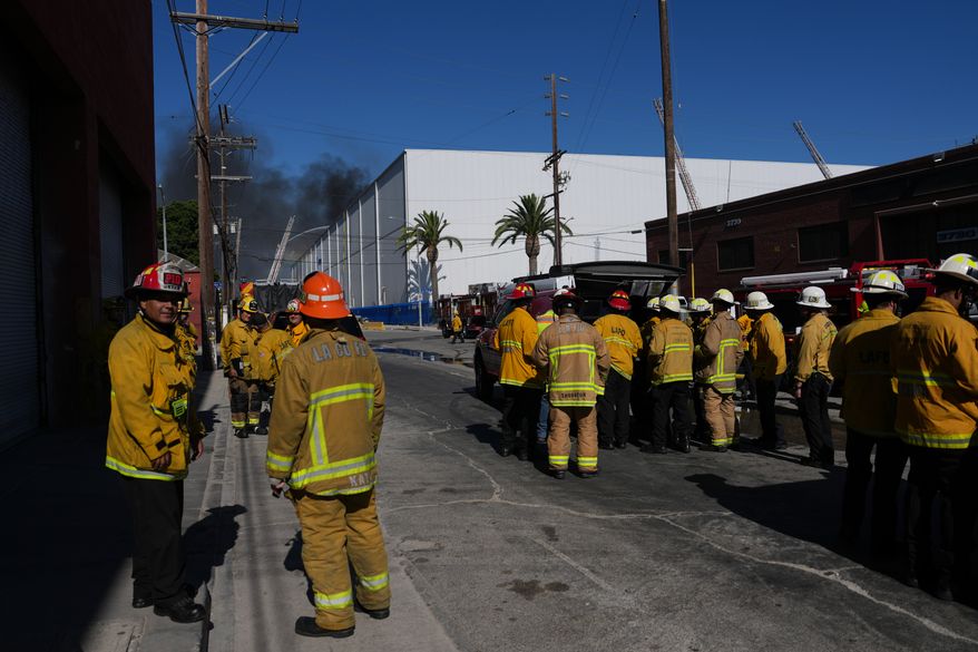 Fire crews stage outside a warehouse in the Boyle Heights section of Los Angeles on Wednesday, June 17, 2026. (AP Photo/Jae C. Hong)