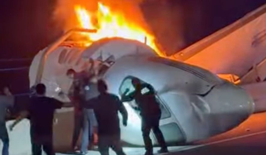 A passenger, top, jumps out of a plane after it crashed on a highway as other people help Tuesday, June 16, 2026, in Laredo, Texas. (Zayra Garza via AP)