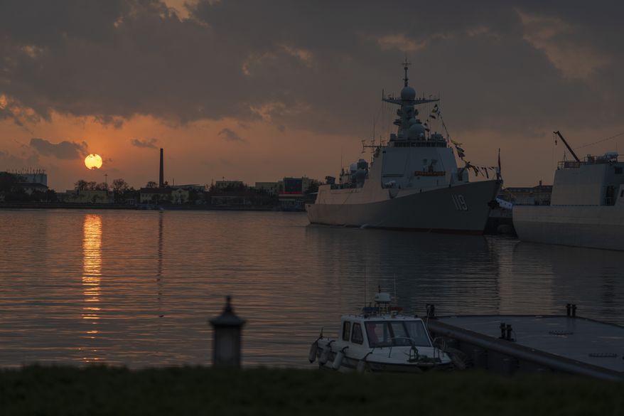The sun sets near the Chinese guided-missile destroyer Guiyang at the end of a public day to mark the 75th anniversary of Chinese People's Liberation Army Navy in Qingdao in eastern China's Shandong province on Tuesday, April 23, 2024. (AP Photo/Ng Han Guan)