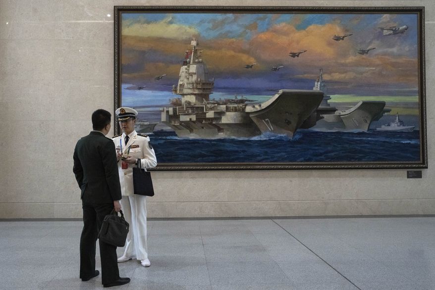 Chinese navy officers chat near a painting of a Chinese aircraft carrier at the Chinese People's Liberation Army Naval Museum in Qingdao in eastern China's Shandong province on Tuesday, April 23, 2024. (AP Photo/Ng Han Guan)