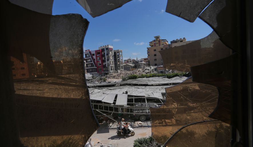 Buildings damaged by Israeli strikes are seen through shattered glass from the Jabal Amel Hospital in the southern port city of Tyre, Lebanon, Thursday, June 18, 2026. (AP Photo/Hassan Ammar)
