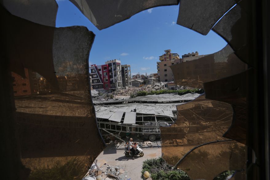 Buildings damaged by Israeli strikes are seen through shattered glass from the Jabal Amel Hospital in the southern port city of Tyre, Lebanon, Thursday, June 18, 2026. (AP Photo/Hassan Ammar)