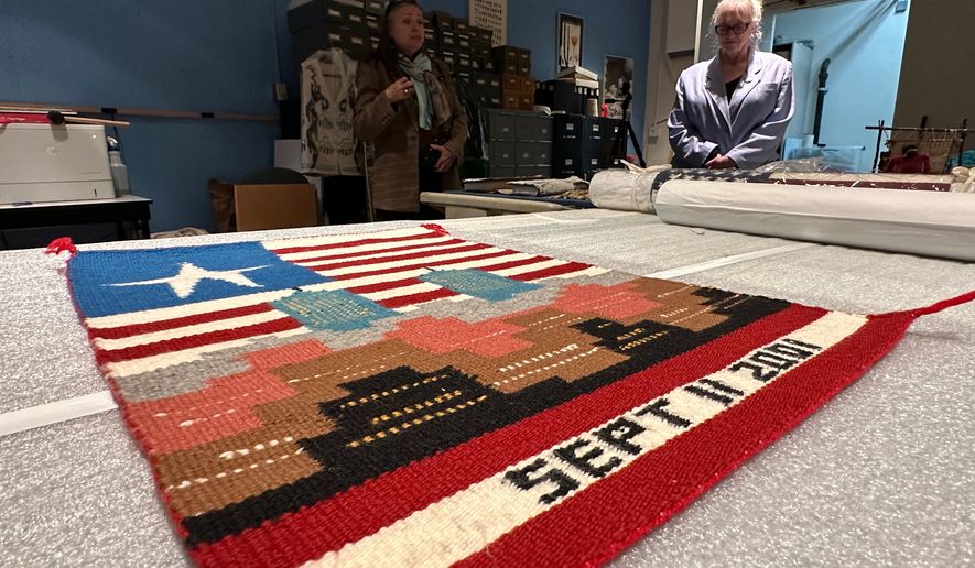 Museum executive director Danyelle Means, left, and head of curatorial affairs Elisa Phelps discuss a weaving by Navajo artist Pauline Thomas as it's prepared for display at the Museum of Indian Arts and Culture in Santa Fe, N.M., on Monday, May 11, 2026. (AP Photo/Susan Montoya Bryan)