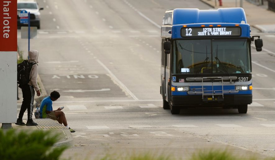People wait for the bus at a transit center Friday, June 5, 2026, in Kansas City, Mo. (AP Photo/Charlie Riedel)