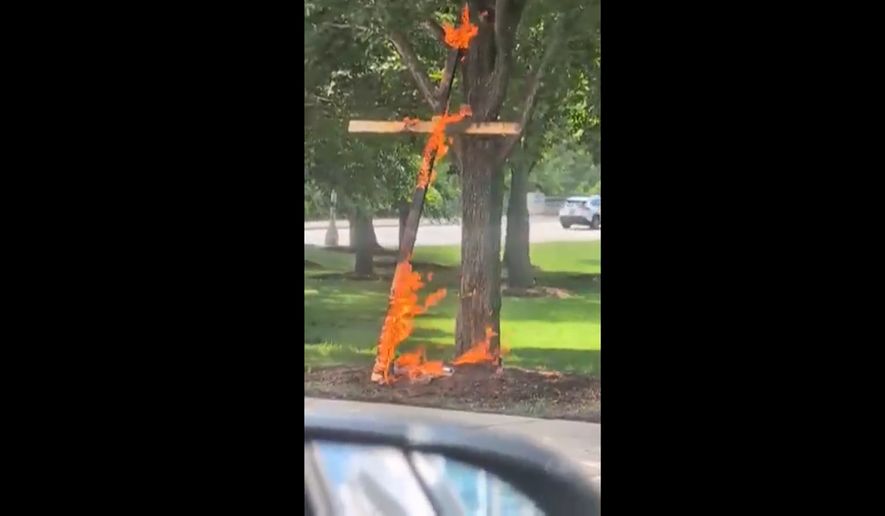 This framegrab from a video taken by motorist Keinika Carlton shows a wooden cross engulfed in bright orange flames as it leans against a tree in Grant Park in Chicago on Tuesday, July 9, 2026. (Keinika Carlton via AP)