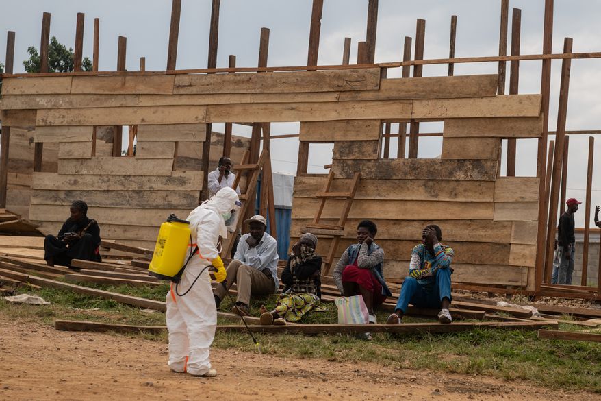 A health worker disinfects the area around a treatment center under construction at the General Hospital in Bunia, Congo, Monday, June 15, 2026. (AP Photo/Moses Sawasawa)