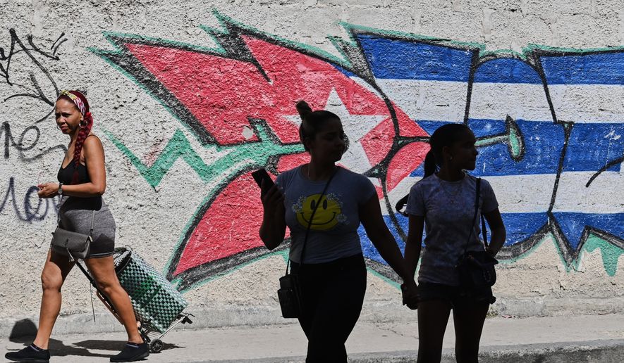 People walk past graffiti in the colors of the Cuban flag in Havana, Cuba, Wednesday, June 17, 2026. (AP Photo/Jorge Luis Banos)