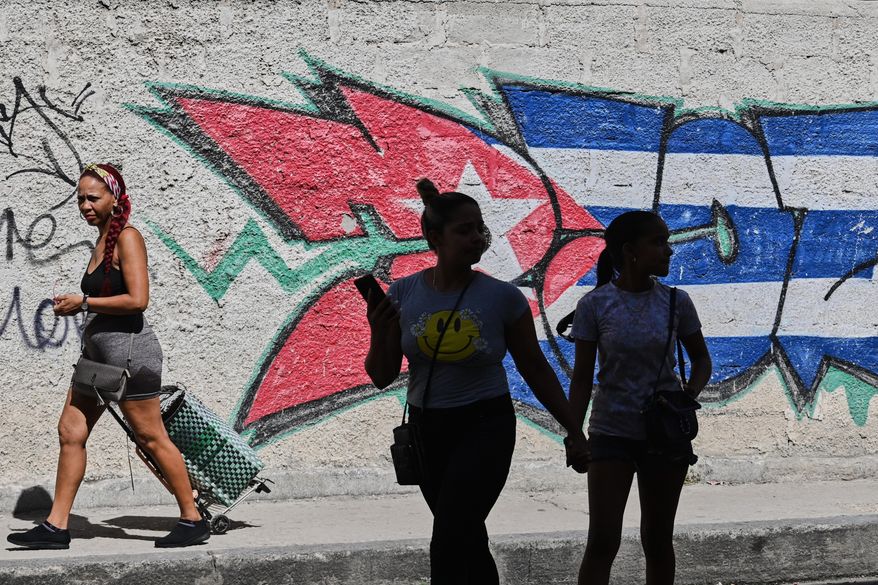 People walk past graffiti in the colors of the Cuban flag in Havana, Cuba, Wednesday, June 17, 2026. (AP Photo/Jorge Luis Banos)