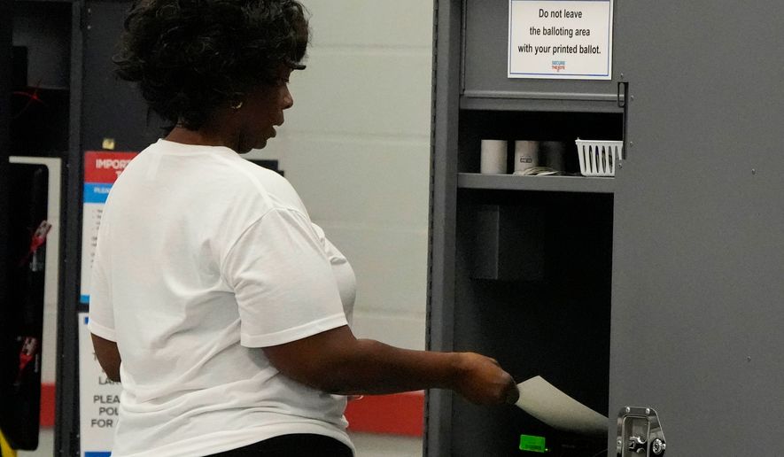 A woman places her paper ballot into a machine after voting in a runoff election at C.T. Martin Recreation Center, Tuesday, June 16, 2026, in Atlanta. (AP Photo/Mike Stewart)