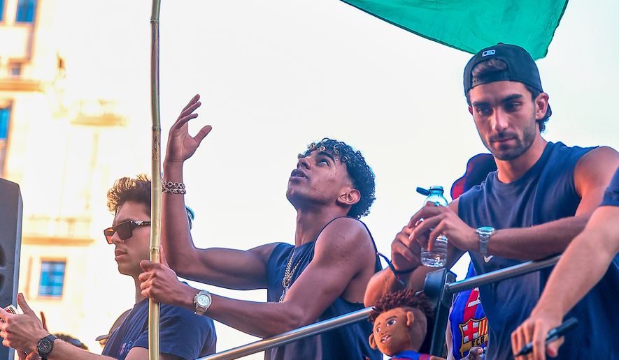 FC Barcelona player Lamine Yamal holds a Palestinian flag as he celebrates with his team atop a bus after winning the Spanish La Liga title in Barcelona, Spain, May 11, 2026. (AP Photo, File)