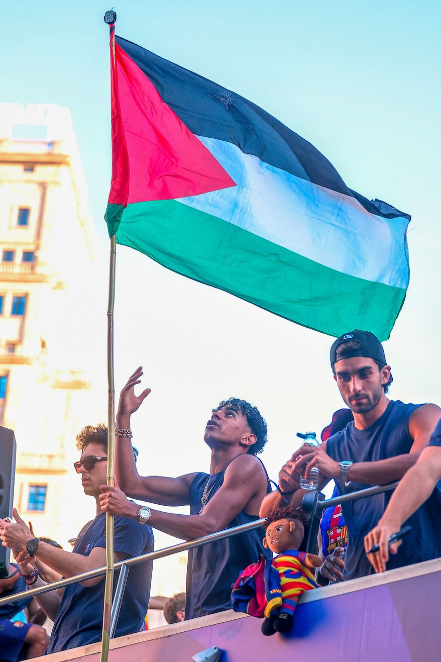 FC Barcelona player Lamine Yamal holds a Palestinian flag as he celebrates with his team atop a bus after winning the Spanish La Liga title in Barcelona, Spain, May 11, 2026. (AP Photo, File)