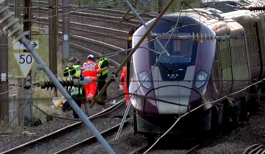 Emergency personnel work on a train on the tracks outside Bedford, England, after a train from Corby to London St. Pancras and another from Nottingham to London St. Pancras, collided on Friday June 19, 2026. (Jamie Lashmar/PA via AP)