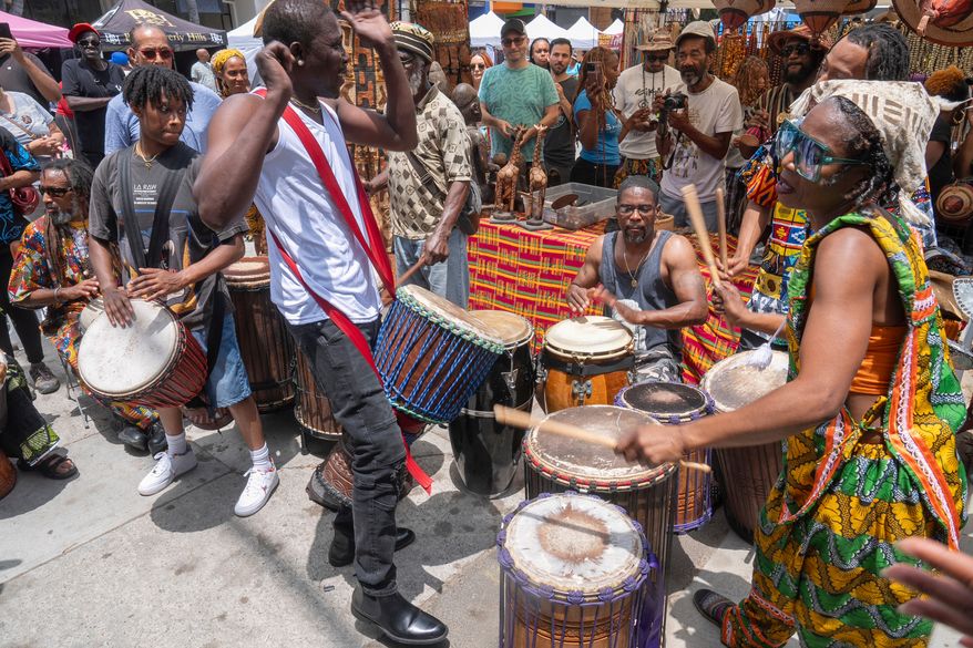 FILE - Drummers form a circle around Sika Dwimfo, better known as the, "Godfather of Leimert Park," during the neighborhood's Juneteenth celebration, June 19, 2024, at Leimert Park in Los Angeles. (AP Photo/Damian Dovarganes, File)