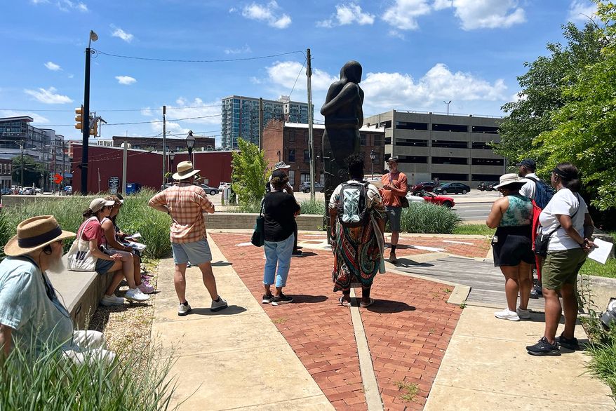 Docent Glyn Hughes, center right, speaks to a group at the Richmond Slavery Reconciliation Statue on Saturday, June 13, 2026, in Richmond, Va. (Religion News Service/Fiona André via AP)