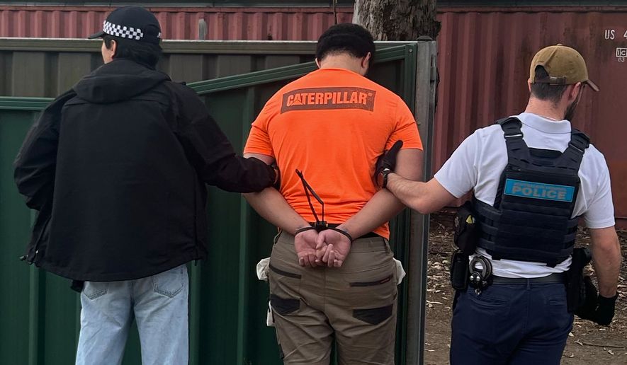 In this photo provided by the Australian Federal Police, a man, center, is arrested by police in Londonderry in western Sydney, Friday, June 19, 2026. (Australian Federal Police via AP)
