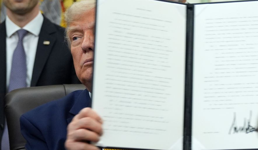 President Donald Trump holds up a signed executive order about quantum computing, in the Oval Office of the White House, Monday, June 22, 2026, in Washington. (AP Photo/Jacquelyn Martin)