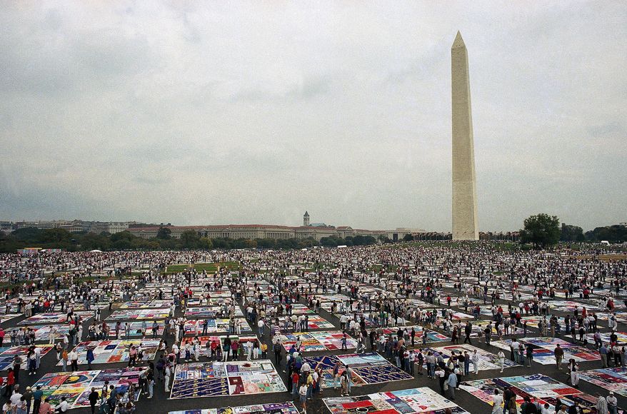 FILE — Thousands of people examine the individual panels of the AIDS quilt as it is displayed on the Mall in Washington on Oct. 11, 1992. (AP Photo/Stephen R. Brown, File)