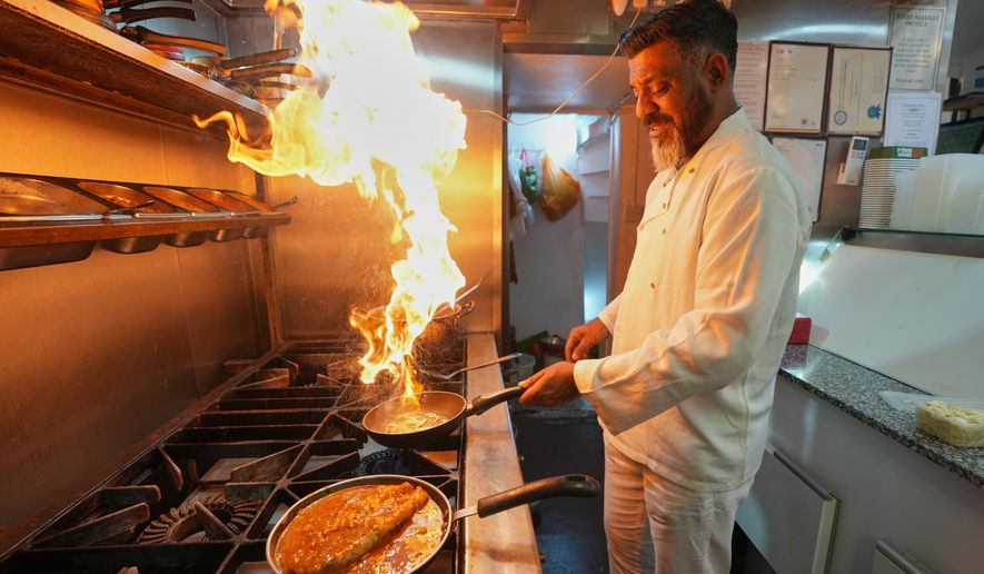 Chef Mohammed Shanoor Ali cooks at a Bangladeshi restaurant in London, Thursday, June 18, 2026. (AP Photo/Kin Cheung)