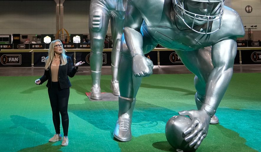 FILE - ESPN anchor Linda Cohn reports next to large images of football players at a fan fest Thursday, Jan. 5, 2023, at the Los Angeles Convention Center in Los Angeles. (AP Photo/Marcio Sanchez, File)
