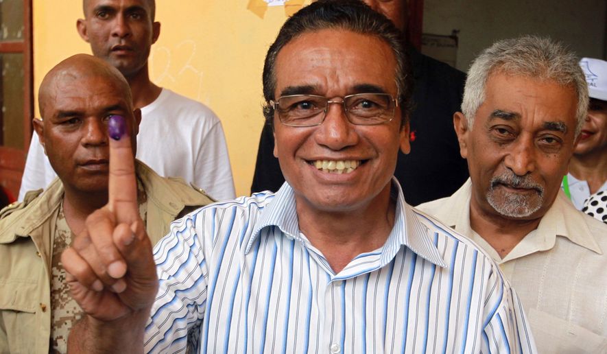 FILE - Fretilin Party leader Francisco "Lu Olo" Guterres, center, shows his inked finger after giving his vote during the presidential election at a polling station in Dili, East Timor, on March 20, 2017. (AP Photo/Kandhi Barnez, File)