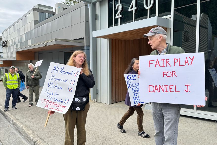 Anjuli Grantham, left, and Ben Muse protest with others outside the Alaska Division of Elections office on Friday, June 12, 2026, in Juneau, Alaska, opposing efforts to block from the ballot a U.S. Senate candidate who shares the same name and party affiliation as the incumbent Republican Dan Sullivan. (AP Photo/Becky Bohrer)