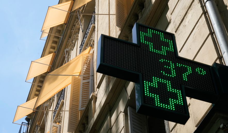 A sign outside a pharmacy displays a temperature of 37 degrees Celsius (98.6 degrees Fahrenheit) in Paris, Sunday, June 21, 2026. (AP Photo/Michel Euler)