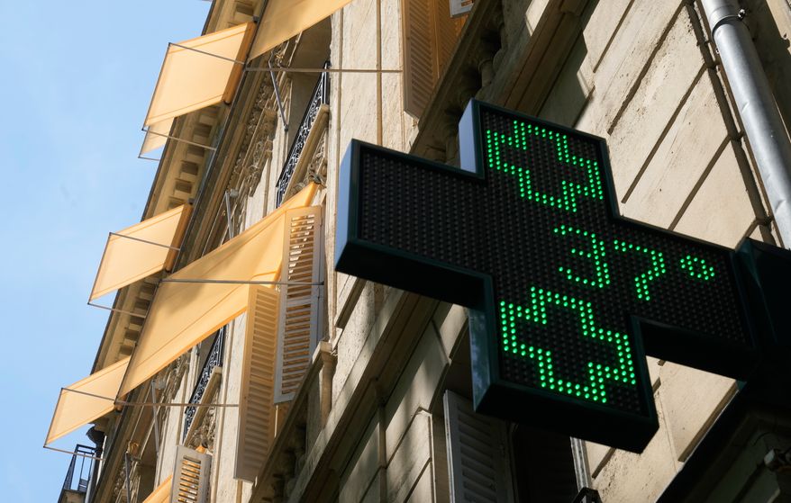A sign outside a pharmacy displays a temperature of 37 degrees Celsius (98.6 degrees Fahrenheit) in Paris, Sunday, June 21, 2026. (AP Photo/Michel Euler)
