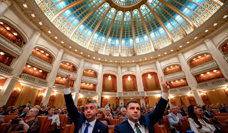 Romanian lawmakers raise their hands at the start of a joint parliament session ahead of a vote of confidence for the new government team led by Romanian Prime Minister designate Adrian Vestea, in Bucharest, Romania, Monday, June 22, 2026. (AP Photo/Vadim Ghirda)