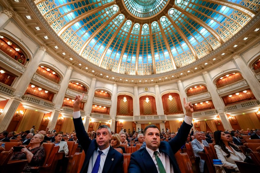 Romanian lawmakers raise their hands at the start of a joint parliament session ahead of a vote of confidence for the new government team led by Romanian Prime Minister designate Adrian Vestea, in Bucharest, Romania, Monday, June 22, 2026. (AP Photo/Vadim Ghirda)