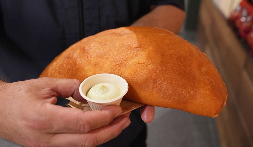 Lazaro Luya, the concession chef at Sol Cubano, displays their special, empanada mundial at Miami Stadium Sunday, June 21, 2026, in Miami Gardens, Fla. (AP Photo/Marta Lavandier)