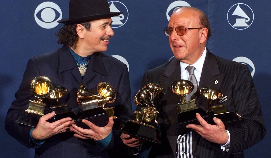 Carlos Santana, left, and producer Clive Davis pose with their Grammys at the 42nd Grammy Awards in Los Angeles, on Feb. 23, 2000. (AP Photo/Reed Saxon, File)