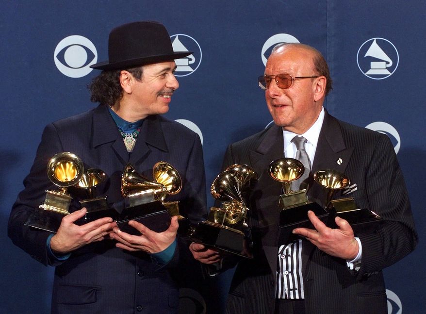 Carlos Santana, left, and producer Clive Davis pose with their Grammys at the 42nd Grammy Awards in Los Angeles, on Feb. 23, 2000. (AP Photo/Reed Saxon, File)