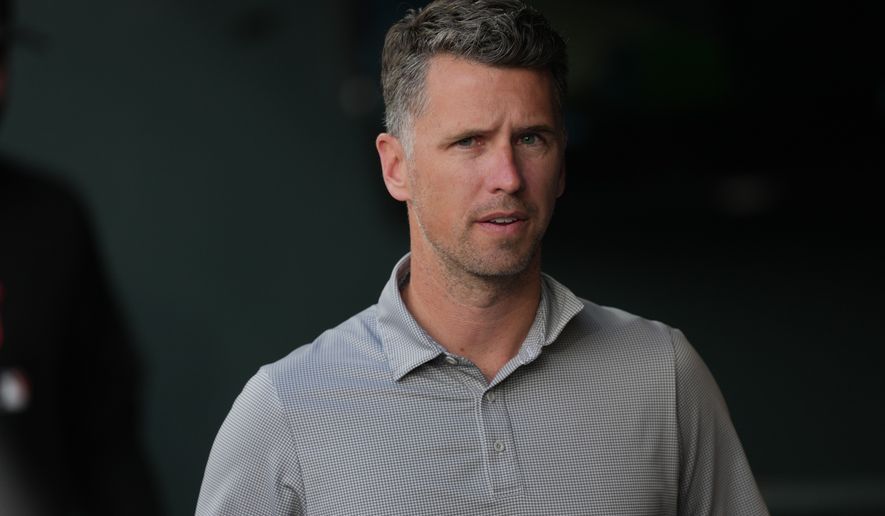 San Francisco Giants president of baseball operations Buster Posey looks on from the dugout as players warm up before a baseball game against the Colorado Rockies, Saturday, May 30, 2026, in Denver. (AP Photo/David Zalubowski)