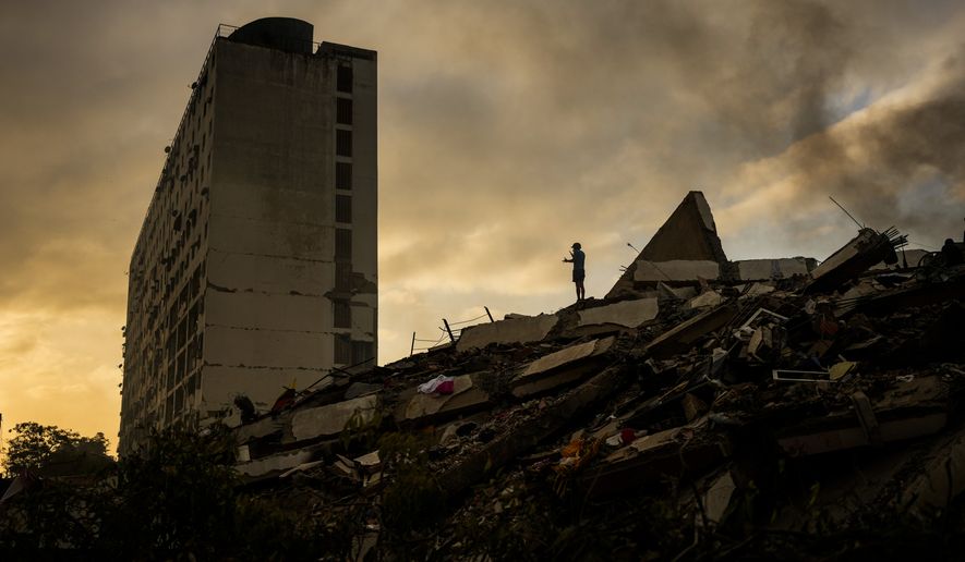 A man stand atop a mountain of rubble three days after twin earthquakes struck, in La Guaira, Venezuela, Saturday, June 27, 2026. (AP Photo/Matias Delacroix)