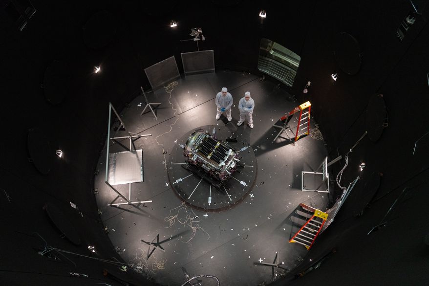 This photo provided by NASA shows Kieran Wilson, LINK’s principal investigator, and Hunter Robertson, a space systems engineer, both at Katalyst Space, standing next to their spacecraft inside the SES (Space Environment Simulator) at NASA’s Goddard Space Flight Center in Greenbelt, Md., April 17, 2026, ahead of thermal vacuum testing. (Sophia Roberts/NASA via AP)