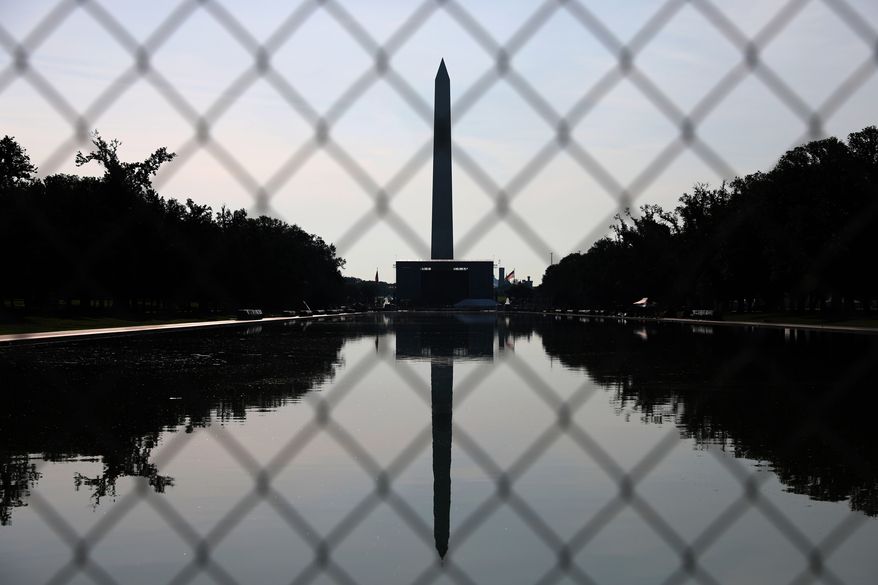 The Washington Monument, reflected in the Lincoln Memorial Reflecting Pool, is seen behind fencing, Tuesday, June 30, 2026, in Washington. (AP Photo/Rahmat Gul)