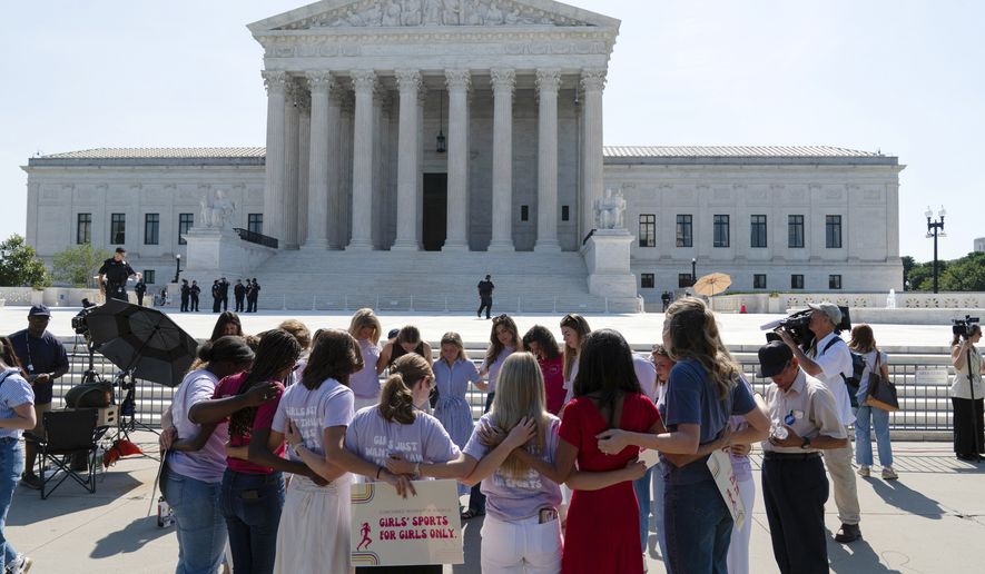 A group prays outside of the Supreme Court ahead of the court's ruling on whether transgender girls and women can play on school athletic teams, Tuesday, June 30, 2026, on Capitol Hill in Washington. (AP Photo/Jose Luis Magana)