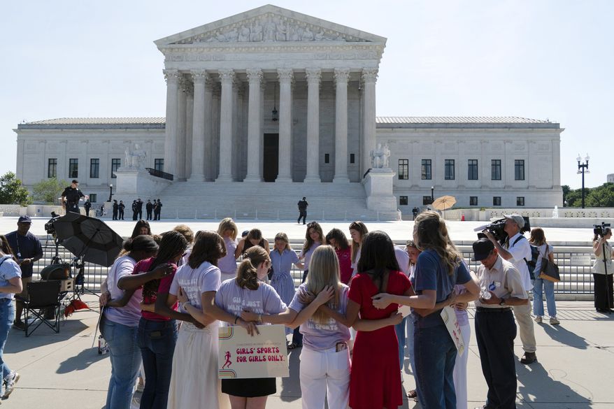 A group prays outside of the Supreme Court ahead of the court's ruling on whether transgender girls and women can play on school athletic teams, Tuesday, June 30, 2026, on Capitol Hill in Washington. (AP Photo/Jose Luis Magana)