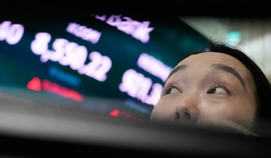 A currency trader watches monitors near a screen showing the Korea Composite Stock Price Index (KOSPI) at the foreign exchange dealing room of the Hana Bank headquarters in Seoul, South Korea, Wednesday, July 1, 2026. (AP Photo/Ahn Young-joon)