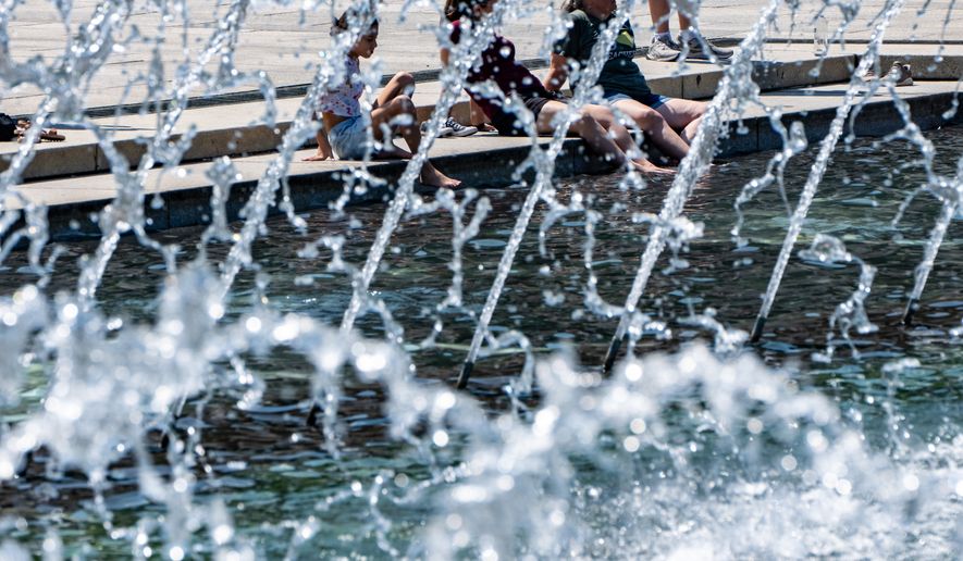 People cool their feet in the fountain at the WWII Memorial, Tuesday, June 30, 2026, in Washington. (AP Photo/Alex Brandon)