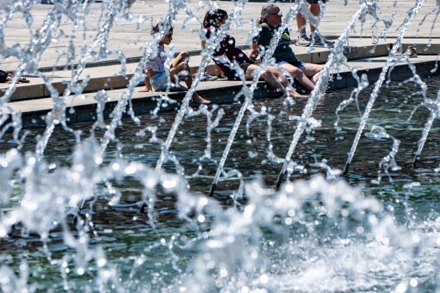 People cool their feet in the fountain at the WWII Memorial, Tuesday, June 30, 2026, in Washington. (AP Photo/Alex Brandon)