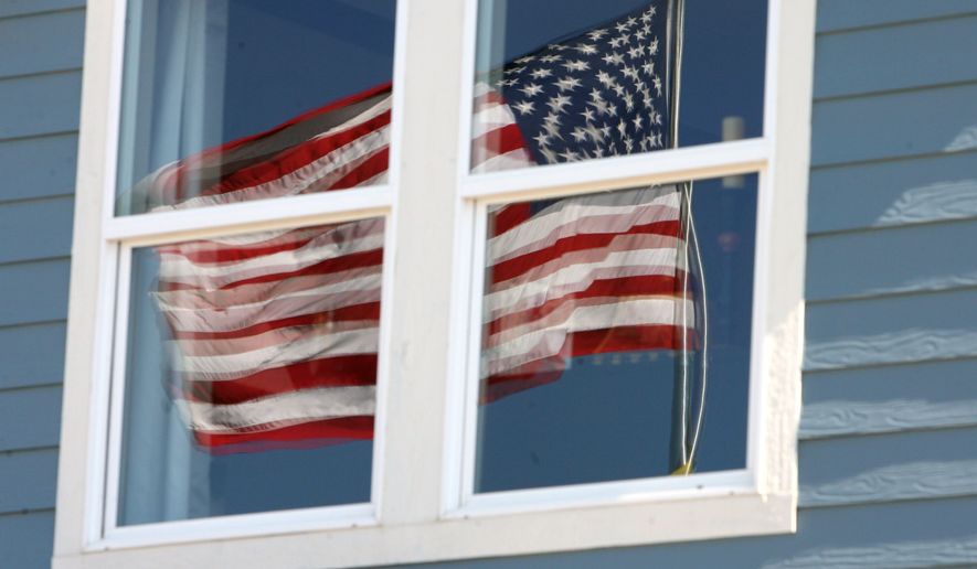 An American flag is reflected in the upstairs windows of a KB Homes model home up for inspection in the Stapleton coach house development on the site of the defunct Stapleton International Airport in east Denver on Wednesday, June 14, 2006. (AP Photo/David Zalubowski)