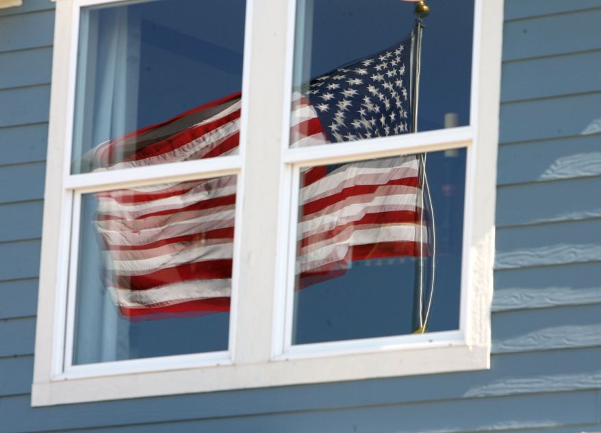An American flag is reflected in the upstairs windows of a KB Homes model home up for inspection in the Stapleton coach house development on the site of the defunct Stapleton International Airport in east Denver on Wednesday, June 14, 2006. (AP Photo/David Zalubowski)