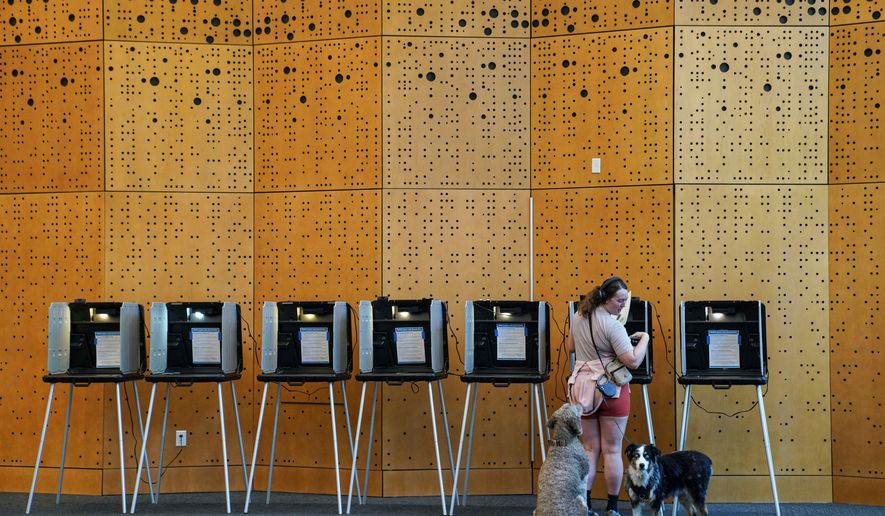 Danielle Grisolano brings her dogs Lincoln and Pepper with her to vote in the Democratic primaries at Denver Public Library, Tuesday, June 30, 2026, in Denver. (AP Photo/Rebecca Slezak)