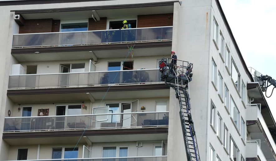 Rescue workers look for victims on upper floors after an apartment block fire in Linkeroever, Belgium, Wednesday, July 1, 2026. (AP Photo/Virginia Mayo)