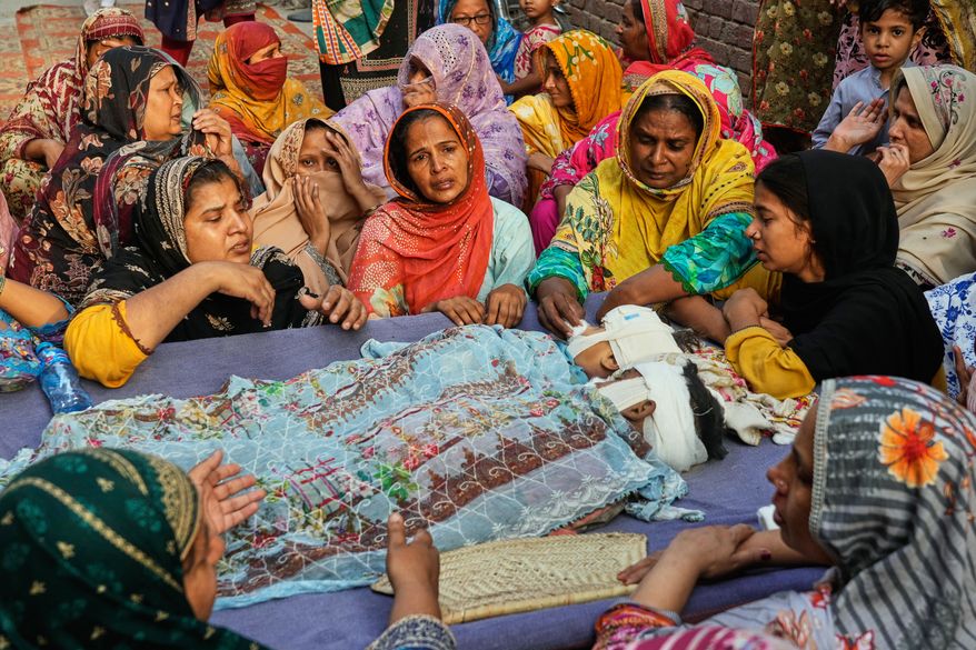 EDS NOTE: GRAPHIC CONTENT - Women mourn around the bodies of their children, who were killed in the roof collapse at a tutoring center that was under construction on the outskirts of Lahore, Pakistan, Wednesday, July 1, 2026. (AP Photo/K.M. Chaudary)