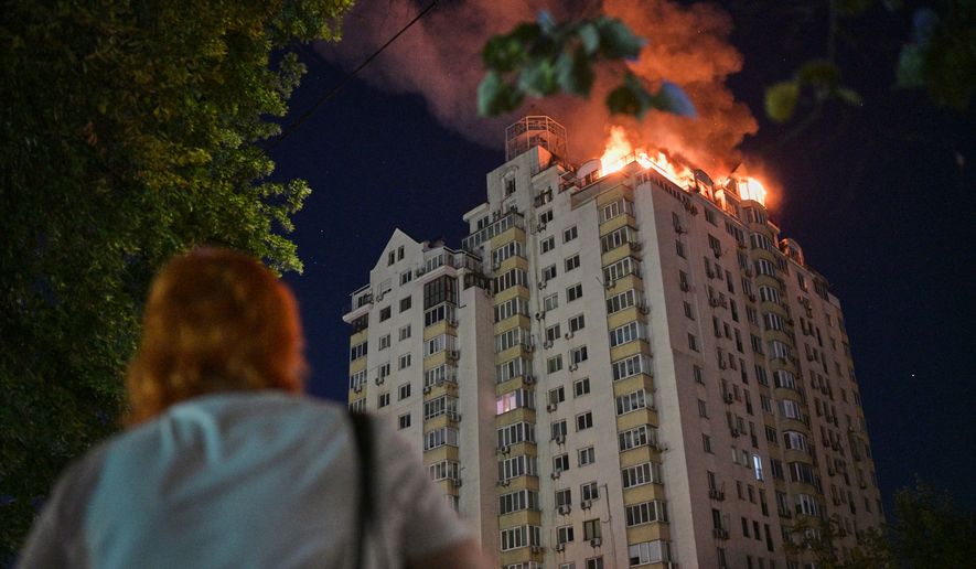 A woman looks at an apartment building burning after a Russian missile attack in Kyiv, Ukraine, Thursday, July 2, 2026. (AP Photo/Danylo Antoniuk)