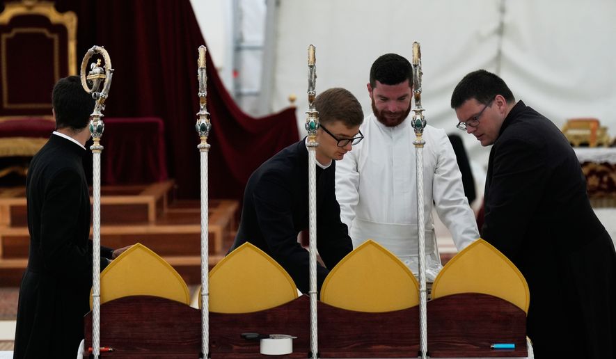 Priests prepare miters and pastoral staffs before the start of a consecration ceremony for four new bishops, in a tent set up outside the Society of St. Pius X seminary, in Econe, Switzerland, Wednesday, July 1, 2026. (AP Photo/Baz Ratner)